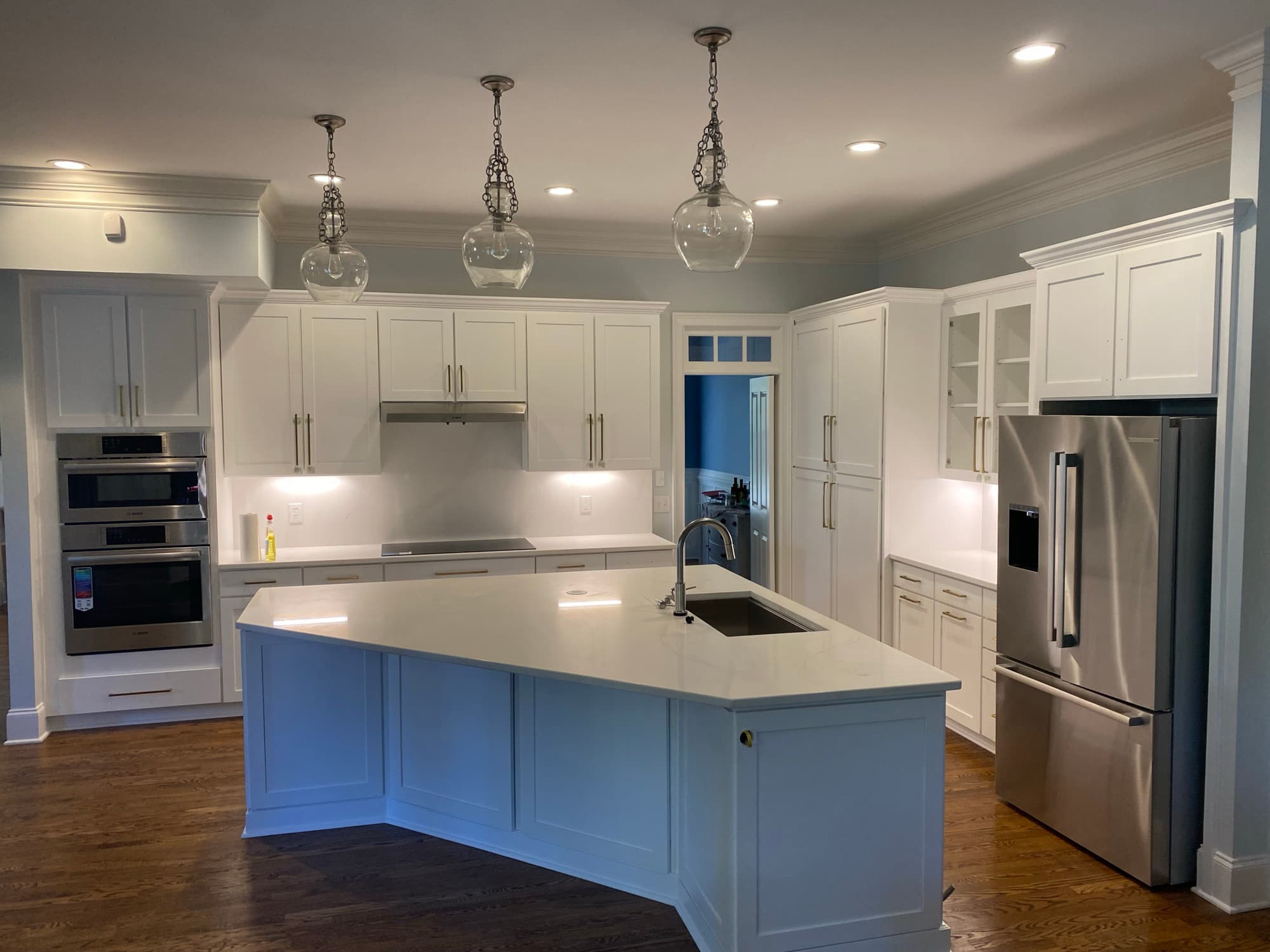 Cary kitchen with white shaker cabinets, glass-front uppers, double wall ovens, and a painted island, built by Jim Cooper Cabinetry